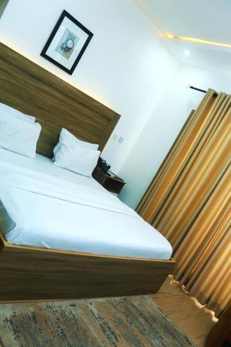 a bedroom with a large bed with a wooden headboard at Hotel Capitol in Ikeja