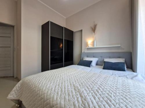 - une chambre avec un grand lit blanc et des oreillers bleus dans l'établissement Apartbaltic - Platan Tower, à Świnoujście