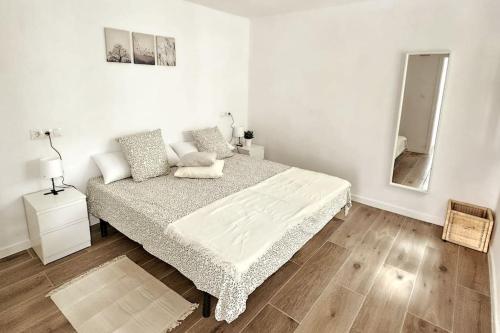 a white bedroom with a bed and a mirror at Apartamento con Playa del Arenal a los pies in Platja de l'Arenal