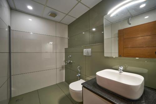a bathroom with a sink and a toilet and a mirror at Venice Iva Residency in Alleppey