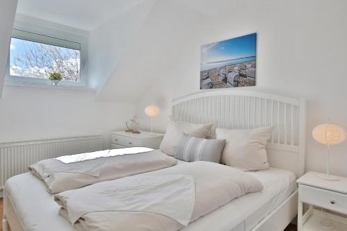 een witte slaapkamer met een groot bed met witte kussens bij Appartemenhaus Linda-Lu Appartementhaus Linda-Lu Appartement 8 in Scharbeutz