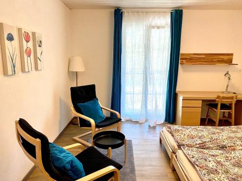 um quarto com uma cama e cadeiras e uma secretária em Vacances à la Ferme des Buffles em Travers