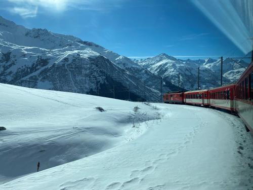 a red train traveling through a snow covered mountain at Apartment Margherita in Sedrun