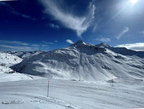 a mountain covered in snow with the sun behind it at Apartment Margherita in Sedrun