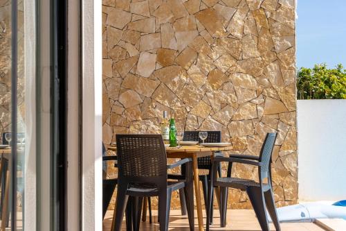 a table and chairs on a patio with a stone wall at Villa Hobie Cat in Sagres
