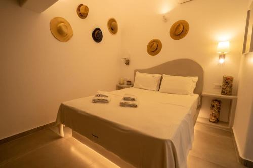 a bedroom with a large white bed with plates on the wall at Acrus Villa Santorini with Heated pool in Karterados