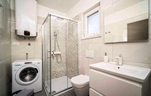 bagno con lavandino e servizi igienici e lavatrice. di Seafront 2-bedroom apartment Nika - Rabac a Rabac