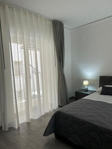 a bedroom with white curtains and a bed and a window at Alloggio Pulcinella in Acerra