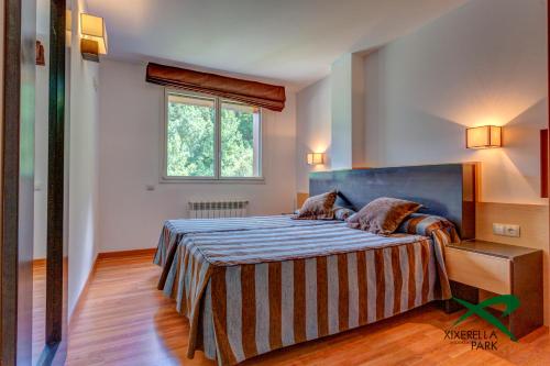 - une chambre avec un lit doté d'une tête de lit bleue et d'une fenêtre dans l'établissement Apartamentos Xixerella Park Resort, à Xixerella