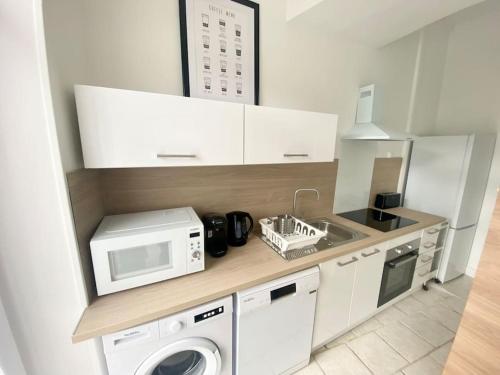une cuisine avec un lave-linge et un micro-ondes dans l'établissement L’escale Jean Jaurès, à Nevers