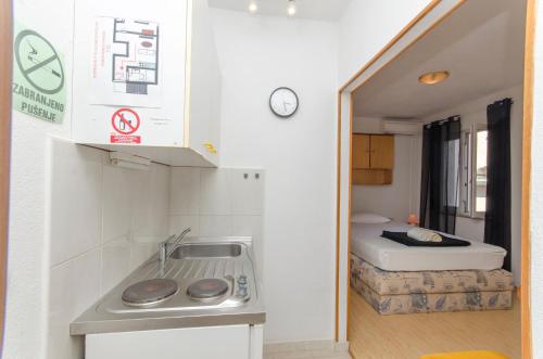 a small kitchen with a sink and a bed in a room at Apartments Banic in Postira