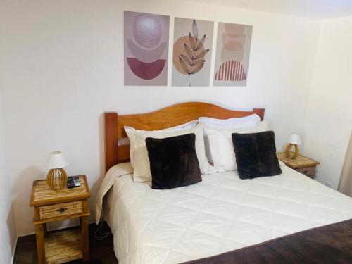 um quarto com uma cama branca e duas mesas de cabeceira em Suítes Andorinhas em Monte Verde