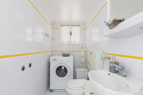 een witte badkamer met een wasmachine en een wastafel bij Luxurious villa, with big garden next to beach in Selianitika