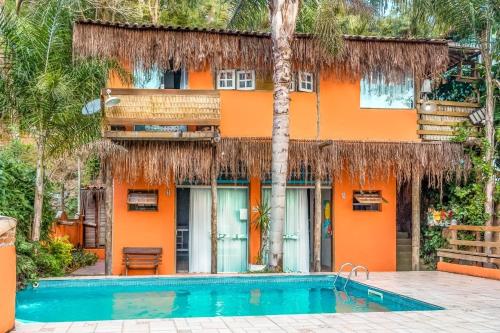 uma casa laranja com uma piscina em frente em Vilarejo do Perequê em Ilhabela