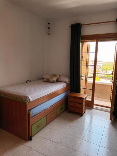 a bedroom with a bed and a large window at Duplex junto a la playa in Arenales del Sol
