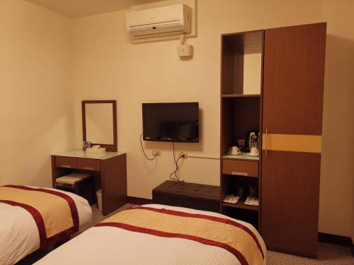 a hotel room with two beds and a television at Mu Xi Ocean View B&B in Beigan