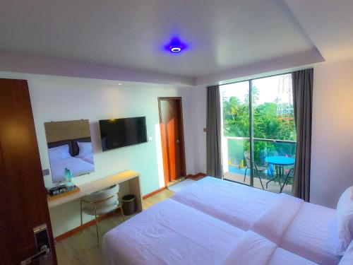 a hotel room with a bed and a desk and a window at Ari Grand Hotel & Spa in Dhangethi