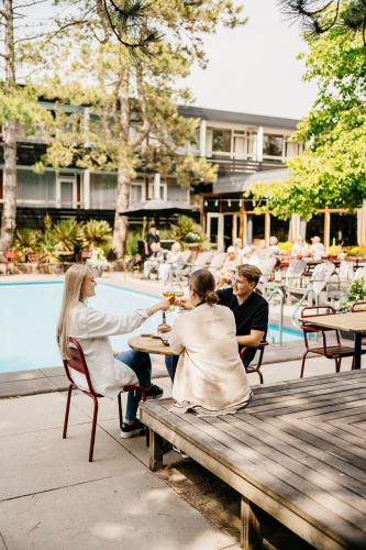 a group of people sitting at a table near a pool at Badhotel Rockanje in Rockanje
