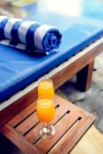 two glasses of orange juice sitting on a wooden table at Jasmine Villa Senggigi in Senggigi 