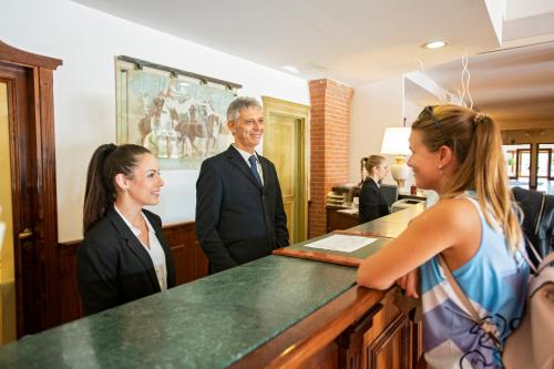 a man and two women standing in front of a counter at Fattoria La Principina Hotel & Congress in Principina Terra