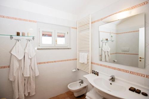a white bathroom with a sink and a toilet at Fattoria La Principina Hotel & Congress in Principina Terra
