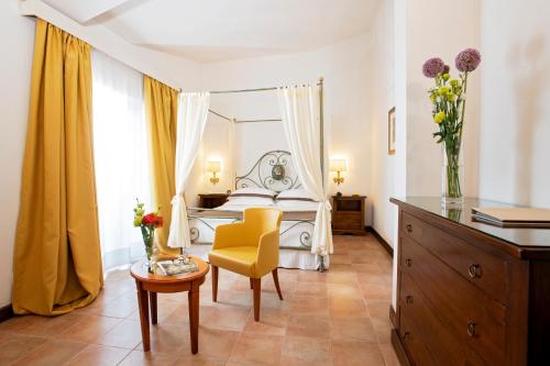 a bedroom with a white bed and a yellow chair at Fattoria La Principina Hotel & Congress in Principina Terra
