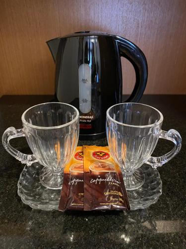 two glass cups sitting on a counter next to a coffee maker at H2 Platinum Lourdes in Belo Horizonte