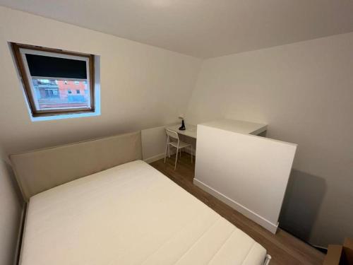 een kleine slaapkamer met een bed en een raam bij Maisonnette Numero 7 in Lille