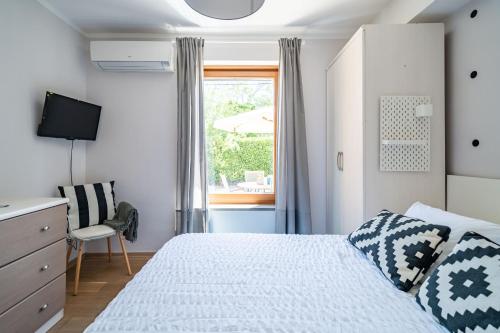 a white bedroom with a bed and a window at Stay U-nique Studio apartment in Orašac in Orasac