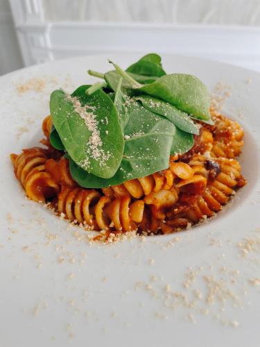 a plate of pasta with green leaves on top at Budapest Airport Eprespark Hotel in Vecsés