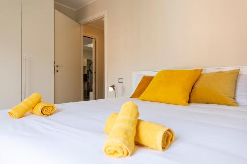 a white bed with yellow pillows and towels on it at Salomone - Mecenate District in Milan