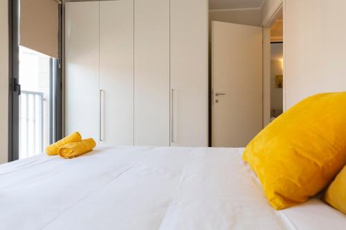 a bedroom with a white bed with yellow pillows at Salomone - Mecenate District in Milan