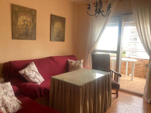 uma sala de estar com um sofá vermelho e uma mesa em APARTAMENTO VALDEMAR PLAYA - WiFi & Aparcamiento em El Puerto de Santa Maria