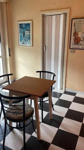 uma mesa de madeira e cadeiras num quarto com piso em xadrez em L’appartamento di Mango e Pistacchio em Segrate