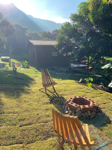 due panche sedute in un cortile con buca per il fuoco di Chalés Vila Do Vale a Vale do Capao