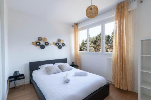 une chambre avec un lit avec des draps blancs et une fenêtre dans l'établissement Cabana & Le Grand Appartement Lumineux, à Mâcon