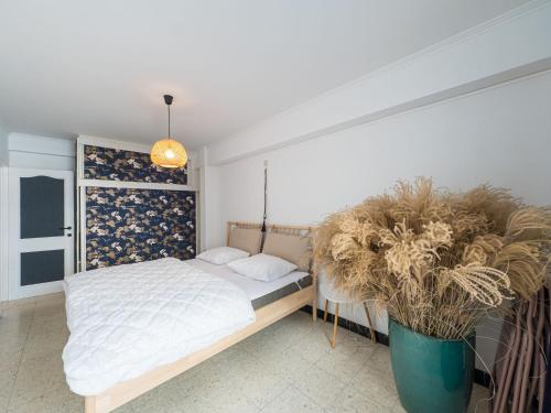 um quarto com uma cama e um vaso de plantas em Rapallo III 3 bedrooms on floor 2 em Middelkerke