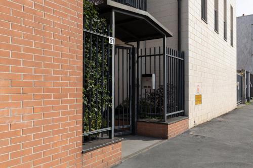a brick building with an open gate with plants at Salomone - Mecenate District in Milan