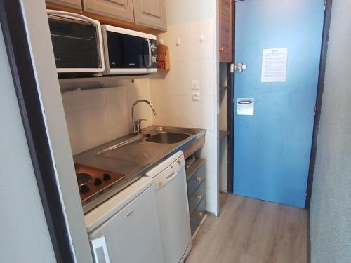 une petite cuisine avec un évier et un micro-ondes dans l'établissement Studio 26m² lumineux, balcon sud, pied des pistes, 3-4 pers, commerces sur place - FR-1-181-2587, à Aime La Plagne