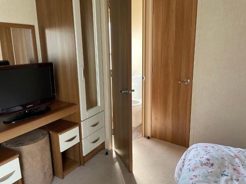 a bedroom with a television and a door to a bathroom at Tags caravan park in Skegness