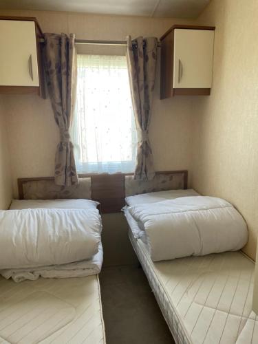 two beds in a small room with a window at Tags caravan park in Skegness