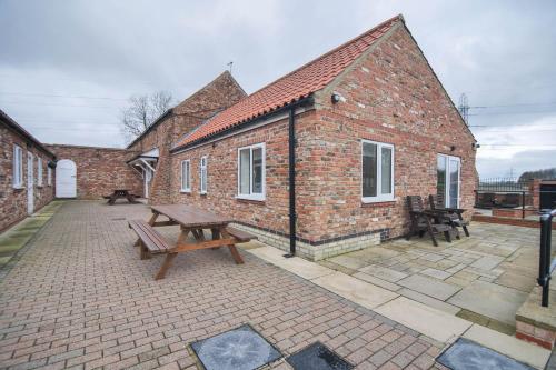 a patio with two picnic tables in front of a brick building at Murton Grange in York