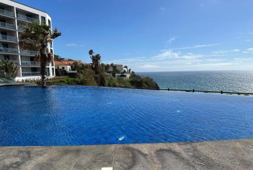 a large swimming pool next to a building and the ocean at Madeira Palace Residences in Funchal