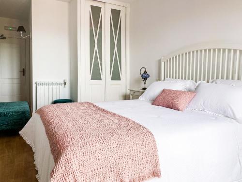 a bedroom with a white bed with a pink blanket on it at Villaprado in Cambados