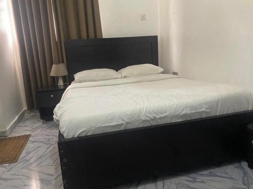 ein Schlafzimmer mit einem großen Bett mit weißer Bettwäsche und Kissen in der Unterkunft Keduu beautiful luxury apartment lekki in Lagos
