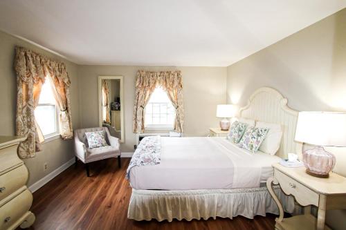 - une chambre avec un grand lit blanc et une chaise dans l'établissement Colonial Inn Seekonk, à Seekonk