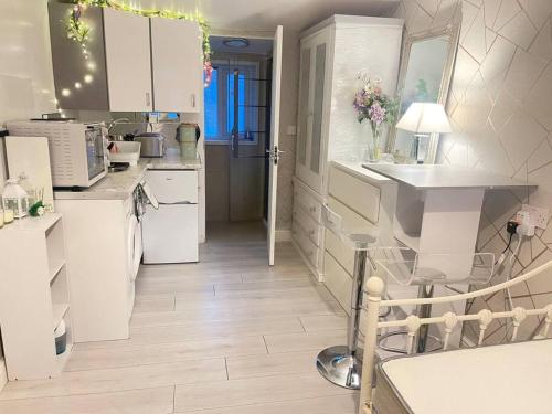 a kitchen with white cabinets and a white floor at Daisy Blossom Studio in Bromley