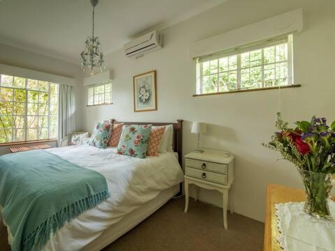 a bedroom with a bed and a table with a vase of flowers at Rose Cottage in Knysna