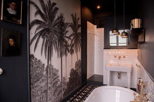 La salle de bains est pourvue d'une baignoire et d'une fresque murale de palmiers. dans l'établissement Les Charmilles, à Sames