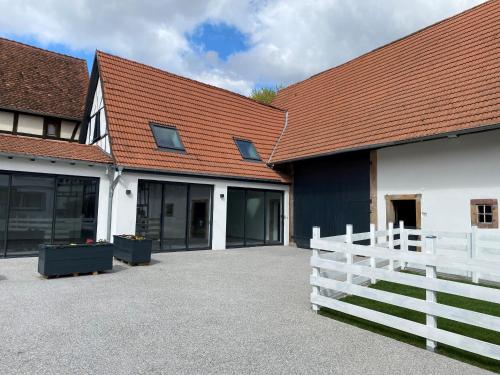 een wit gebouw met een rood dak en een wit hek bij A la ferme in Kurtzenhouse